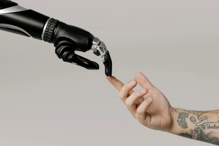 Mano de robot tocando mano humana que representa el desarrollo de la Inteligencia Artificial General y comercial